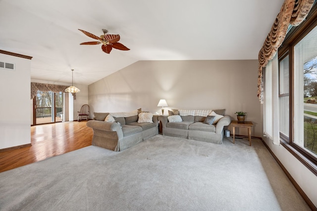 living area with lofted ceiling, ceiling fan with notable chandelier, visible vents, baseboards, and carpet