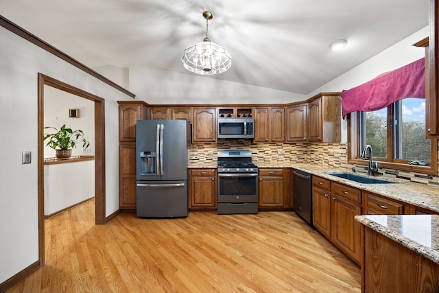 kitchen with stainless steel appliances, light wood finished floors, backsplash, and a sink