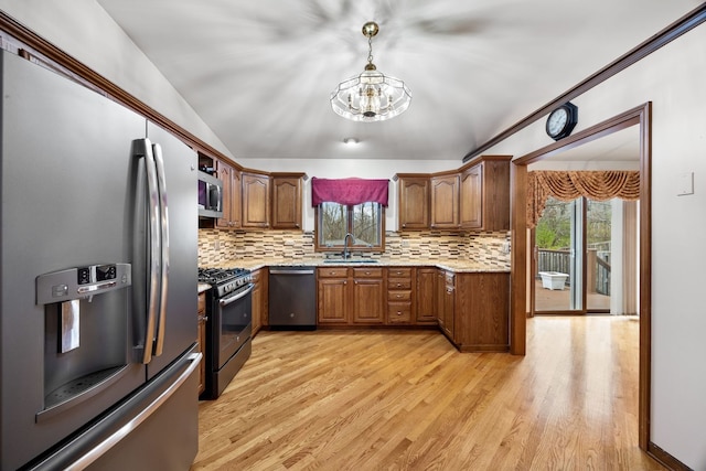 kitchen featuring appliances with stainless steel finishes, light wood-type flooring, a sink, and a healthy amount of sunlight