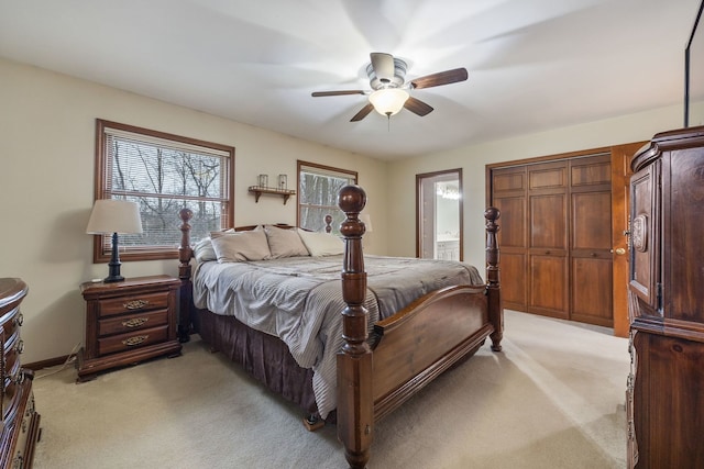 bedroom with a ceiling fan, baseboards, light colored carpet, and ensuite bath