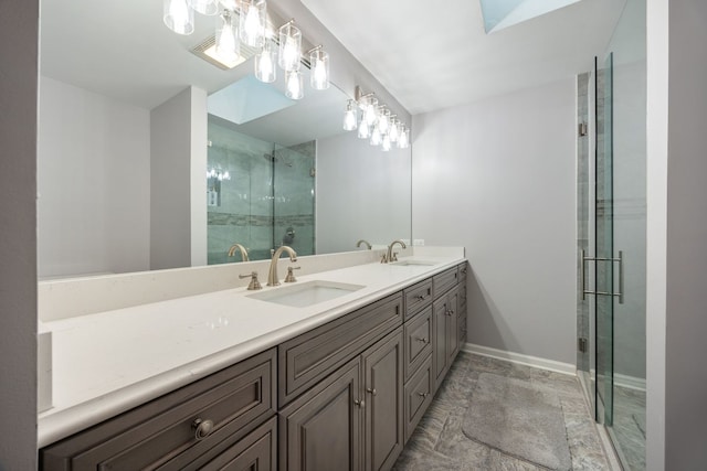 full bathroom with double vanity, a stall shower, a sink, and baseboards