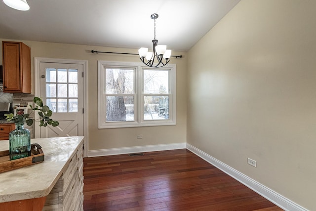 unfurnished dining area with a chandelier and dark wood-type flooring