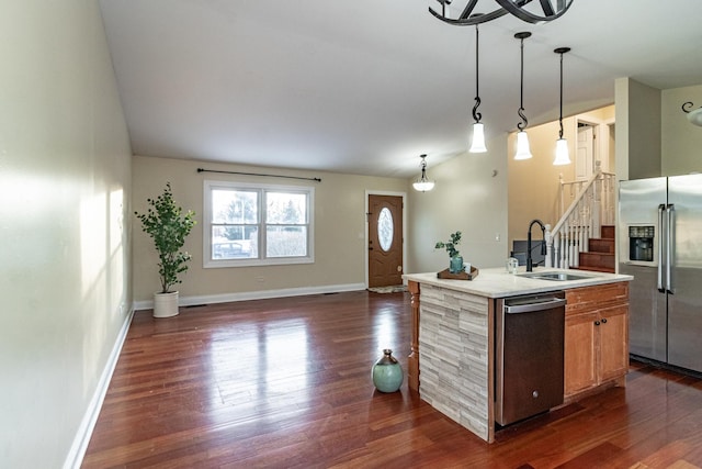 kitchen featuring sink, stainless steel appliances, dark hardwood / wood-style flooring, pendant lighting, and a kitchen island with sink