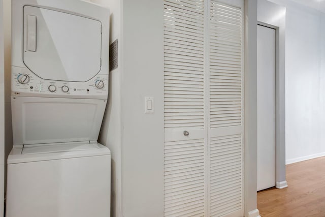 laundry area featuring light wood-type flooring and stacked washer / drying machine