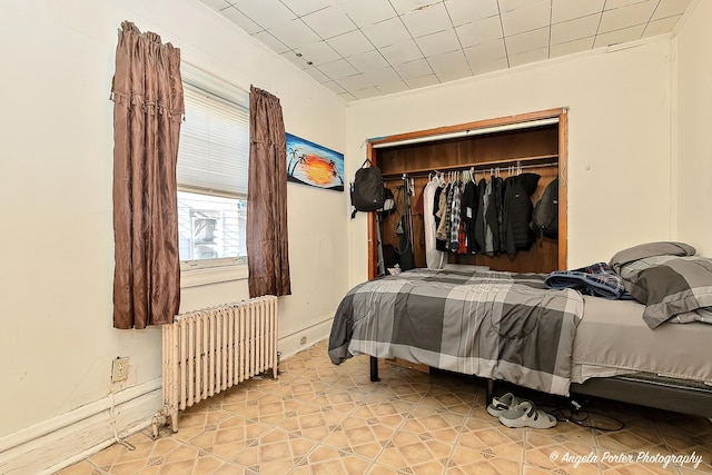 bedroom with radiator heating unit, a closet, and crown molding