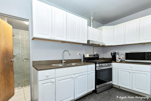 kitchen with dark tile patterned floors, sink, white cabinets, and appliances with stainless steel finishes