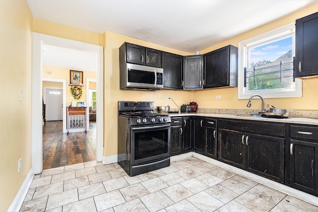 kitchen with black range with gas stovetop, light hardwood / wood-style floors, and sink