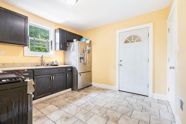 kitchen with stainless steel fridge with ice dispenser, sink, stove, and dark brown cabinets