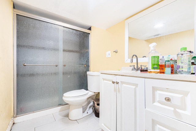 bathroom featuring toilet, vanity, tile patterned floors, and a shower with door