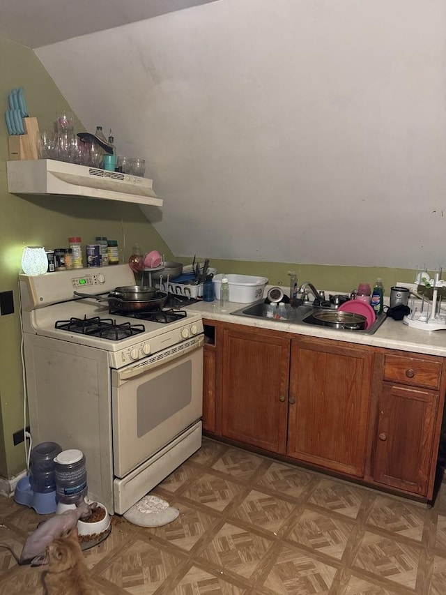 kitchen with light parquet floors, sink, vaulted ceiling, white range with gas cooktop, and extractor fan