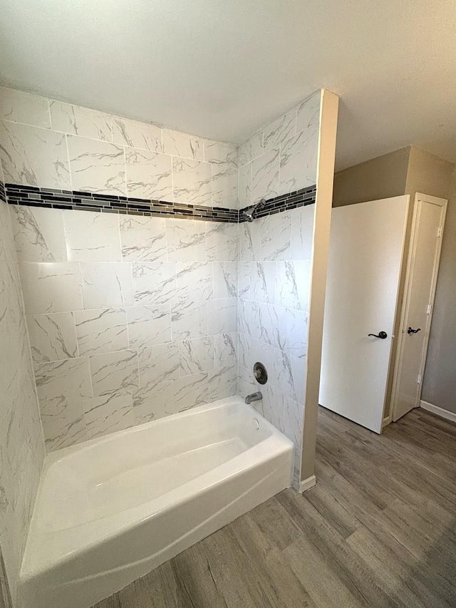 bathroom with hardwood / wood-style flooring and tiled shower / bath