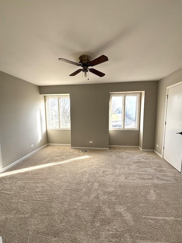 empty room with light carpet, ceiling fan, and a healthy amount of sunlight