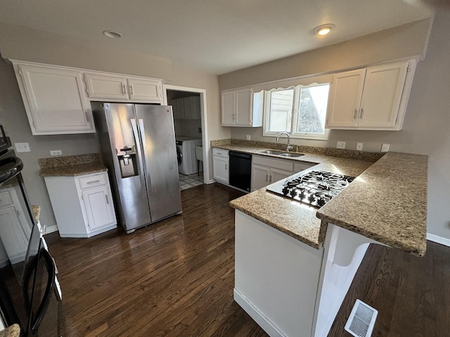 kitchen with sink, washing machine and dryer, dark hardwood / wood-style flooring, white cabinets, and black appliances