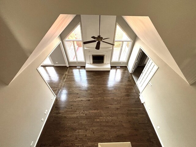 unfurnished living room featuring plenty of natural light, ceiling fan, dark hardwood / wood-style flooring, and a towering ceiling