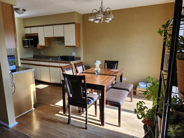 dining room with light hardwood / wood-style floors, a notable chandelier, and sink