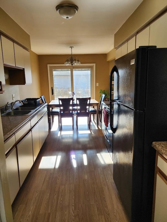 kitchen with dark hardwood / wood-style flooring, sink, black appliances, a notable chandelier, and white cabinetry