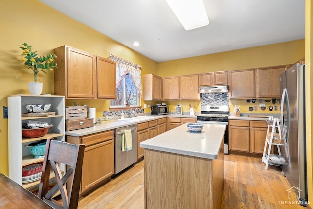 kitchen with sink, stainless steel appliances, decorative backsplash, a kitchen island, and light wood-type flooring