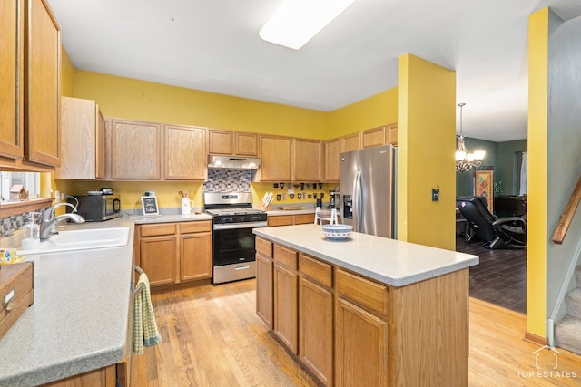 kitchen featuring stainless steel appliances, sink, a notable chandelier, a center island, and light hardwood / wood-style floors