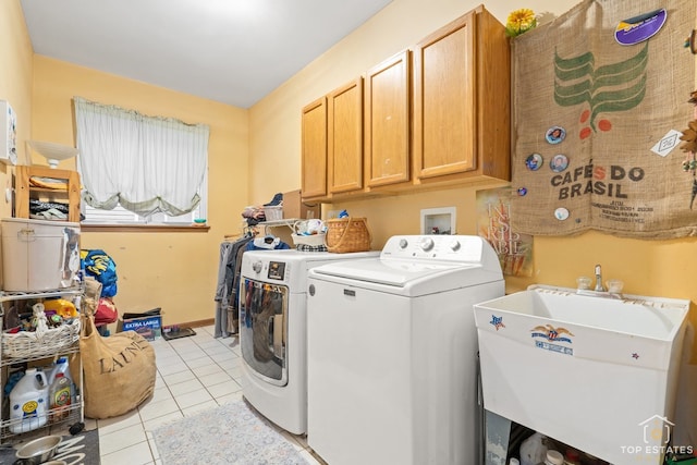 laundry area featuring washer and clothes dryer, sink, light tile patterned floors, and cabinets