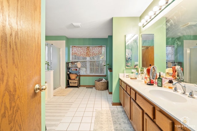 bathroom with tile patterned flooring, vanity, and walk in shower