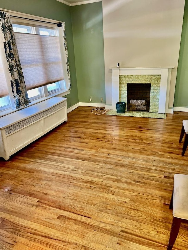 unfurnished living room featuring radiator heating unit, plenty of natural light, and light hardwood / wood-style flooring