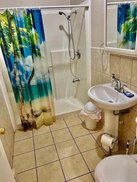 bathroom featuring toilet, tile patterned flooring, tile walls, and walk in shower