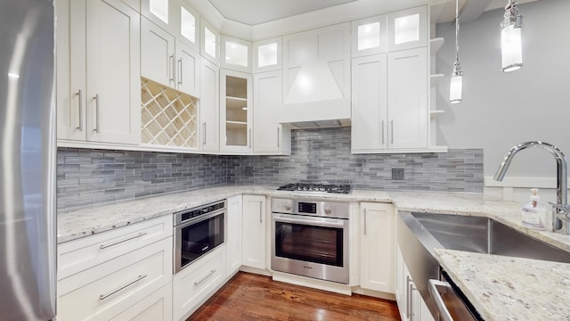 kitchen with appliances with stainless steel finishes, decorative light fixtures, white cabinetry, and light stone counters