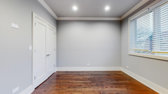 empty room with dark hardwood / wood-style flooring and crown molding