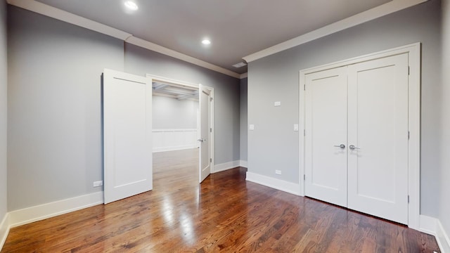 unfurnished bedroom featuring a closet, dark hardwood / wood-style flooring, and ornamental molding