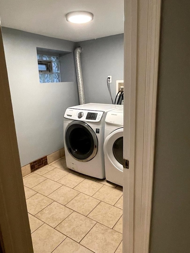 laundry area with independent washer and dryer and light tile patterned floors