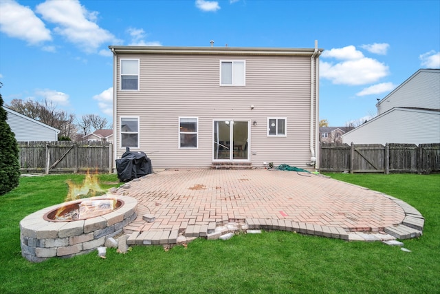 rear view of property with a patio area, a yard, and an outdoor fire pit