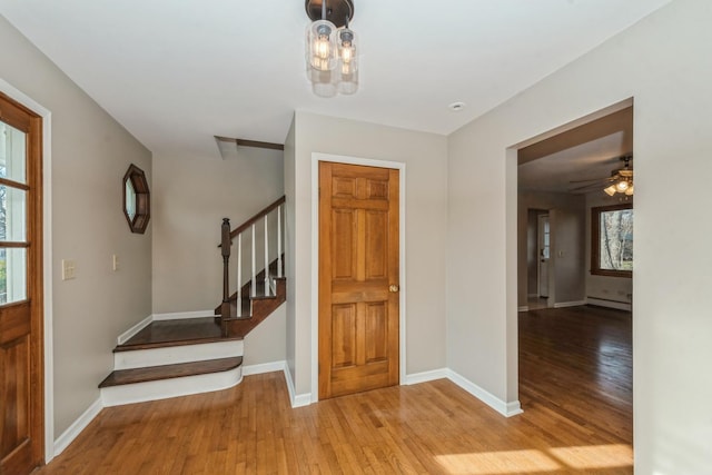 foyer entrance featuring a healthy amount of sunlight, ceiling fan, light hardwood / wood-style floors, and a baseboard heating unit