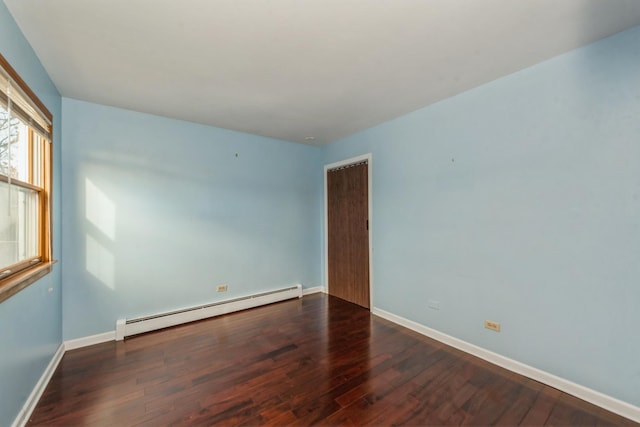 empty room featuring dark wood-type flooring and a baseboard heating unit