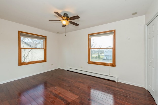 empty room with dark wood-type flooring, ceiling fan, and a baseboard heating unit