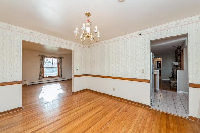 spare room featuring a chandelier, a baseboard radiator, and wood-type flooring