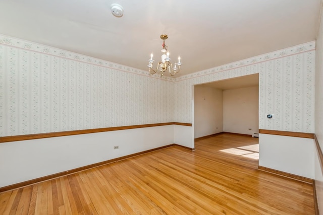 unfurnished room with hardwood / wood-style floors, a baseboard heating unit, and an inviting chandelier