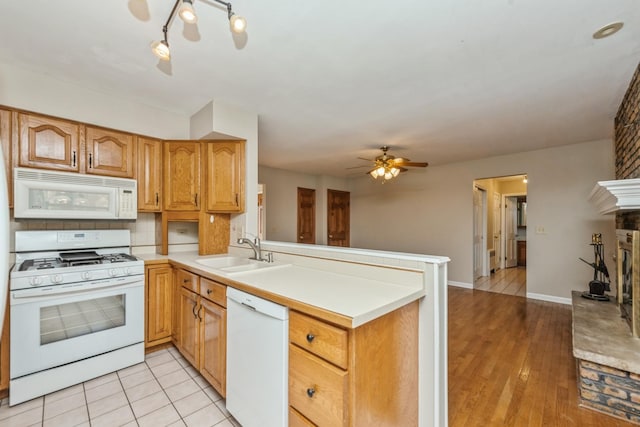 kitchen featuring kitchen peninsula, white appliances, ceiling fan, sink, and a fireplace