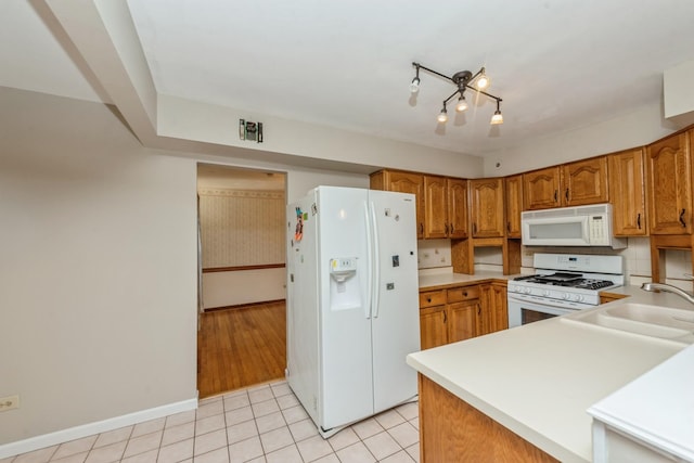 kitchen featuring light tile patterned floors, white appliances, backsplash, and sink