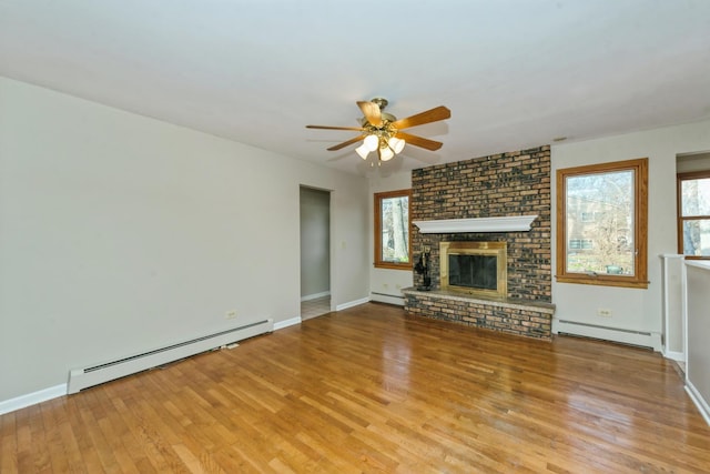 unfurnished living room featuring light hardwood / wood-style floors, a brick fireplace, and baseboard heating