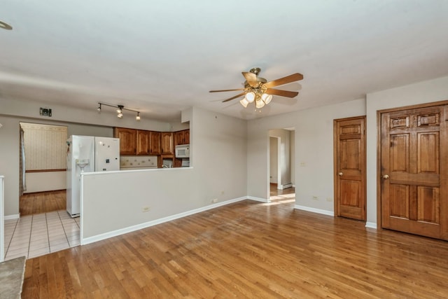 unfurnished living room featuring ceiling fan and light wood-type flooring