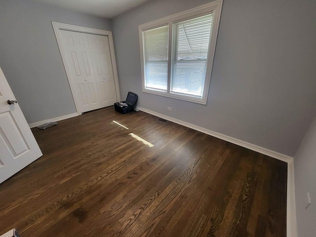 unfurnished bedroom with dark hardwood / wood-style flooring and a closet