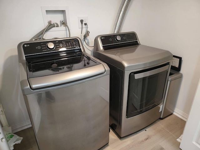 washroom with light wood-type flooring and washing machine and clothes dryer