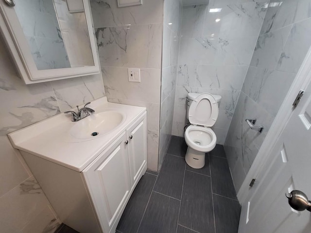 bathroom with vanity, toilet, and tile walls