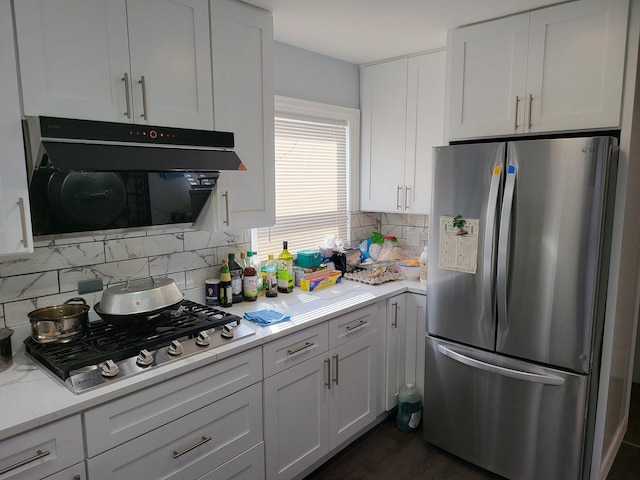 kitchen featuring white cabinets, range hood, tasteful backsplash, light stone counters, and stainless steel appliances