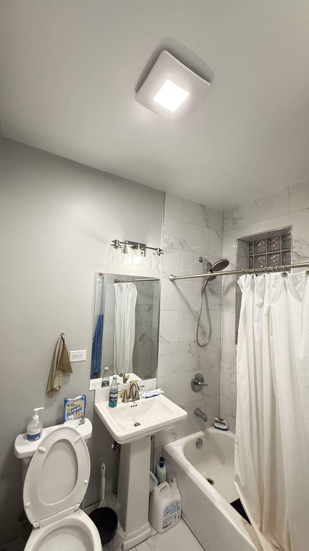 bathroom featuring shower / bath combination with curtain and toilet