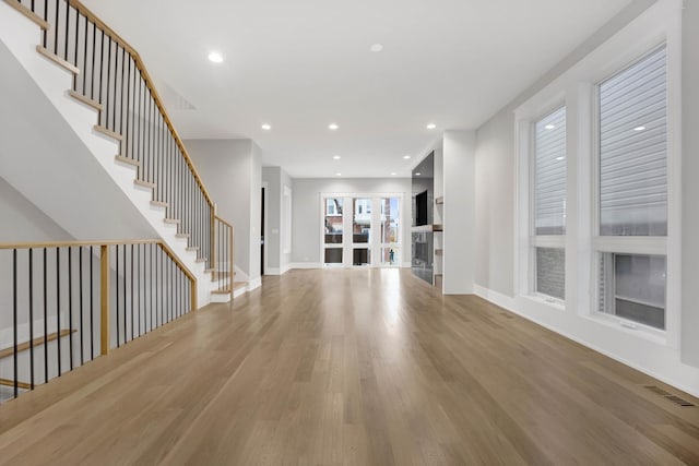 unfurnished living room with stairway, visible vents, wood finished floors, and recessed lighting