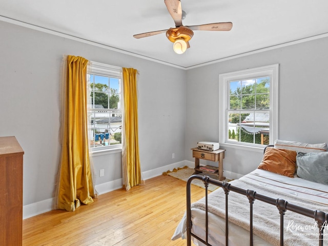 bedroom featuring ceiling fan, crown molding, light hardwood / wood-style flooring, and multiple windows