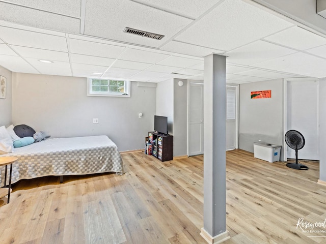 bedroom with a paneled ceiling and light hardwood / wood-style flooring