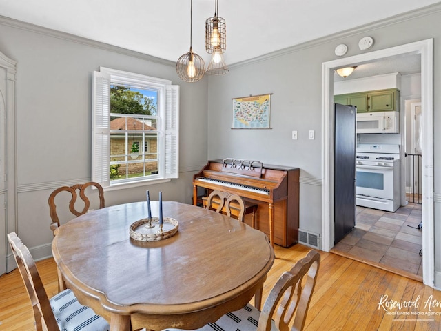 dining area featuring ornamental molding and light wood-type flooring