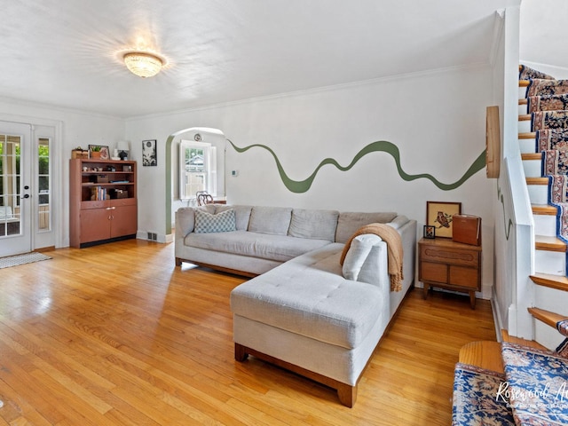 living room with a wealth of natural light, crown molding, and light wood-type flooring